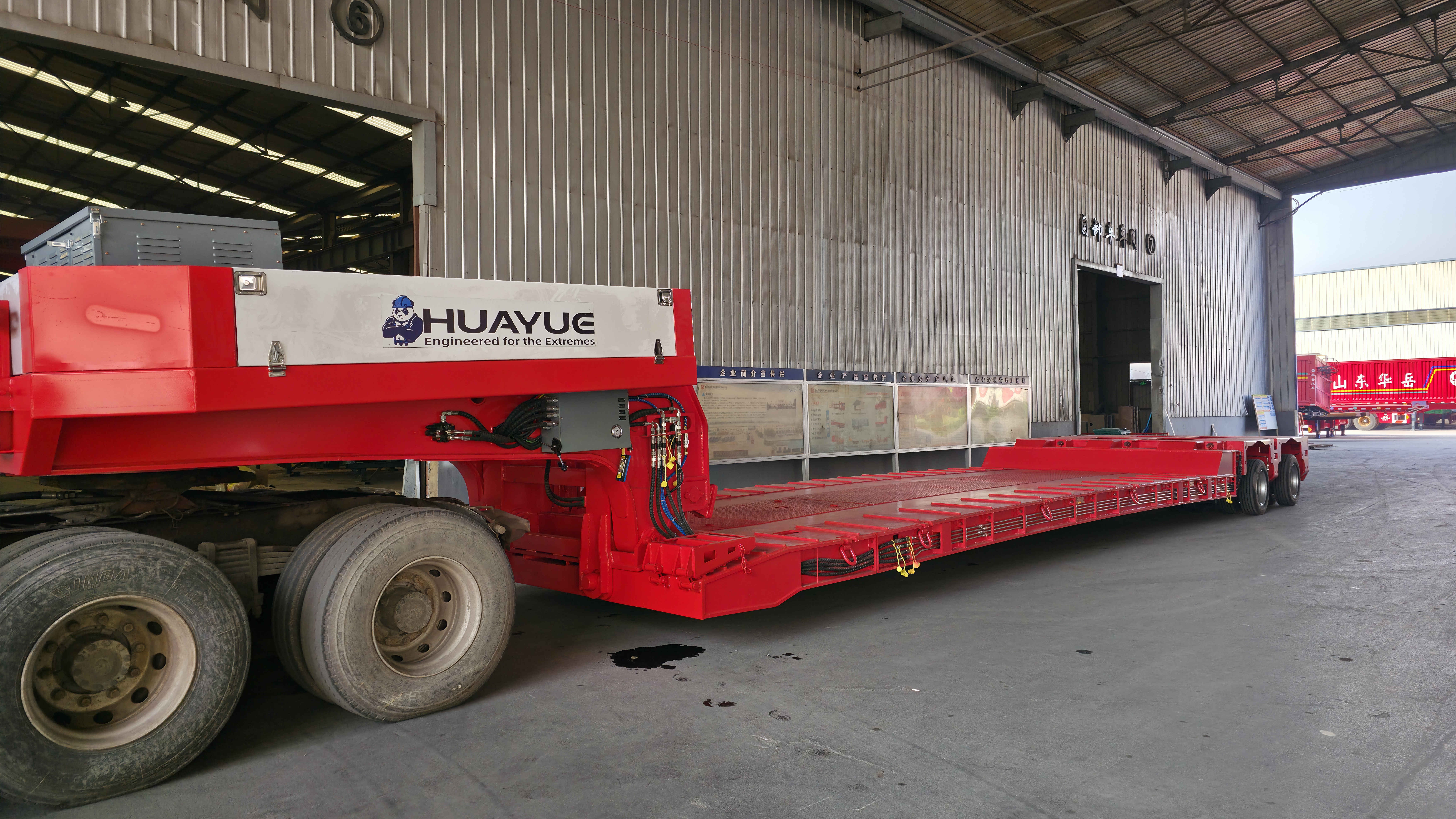 Side profile view of the green HUAYUE 2-axle extendable removable gooseneck lowboy semi-trailer in a manufacturing facility, fully assembled