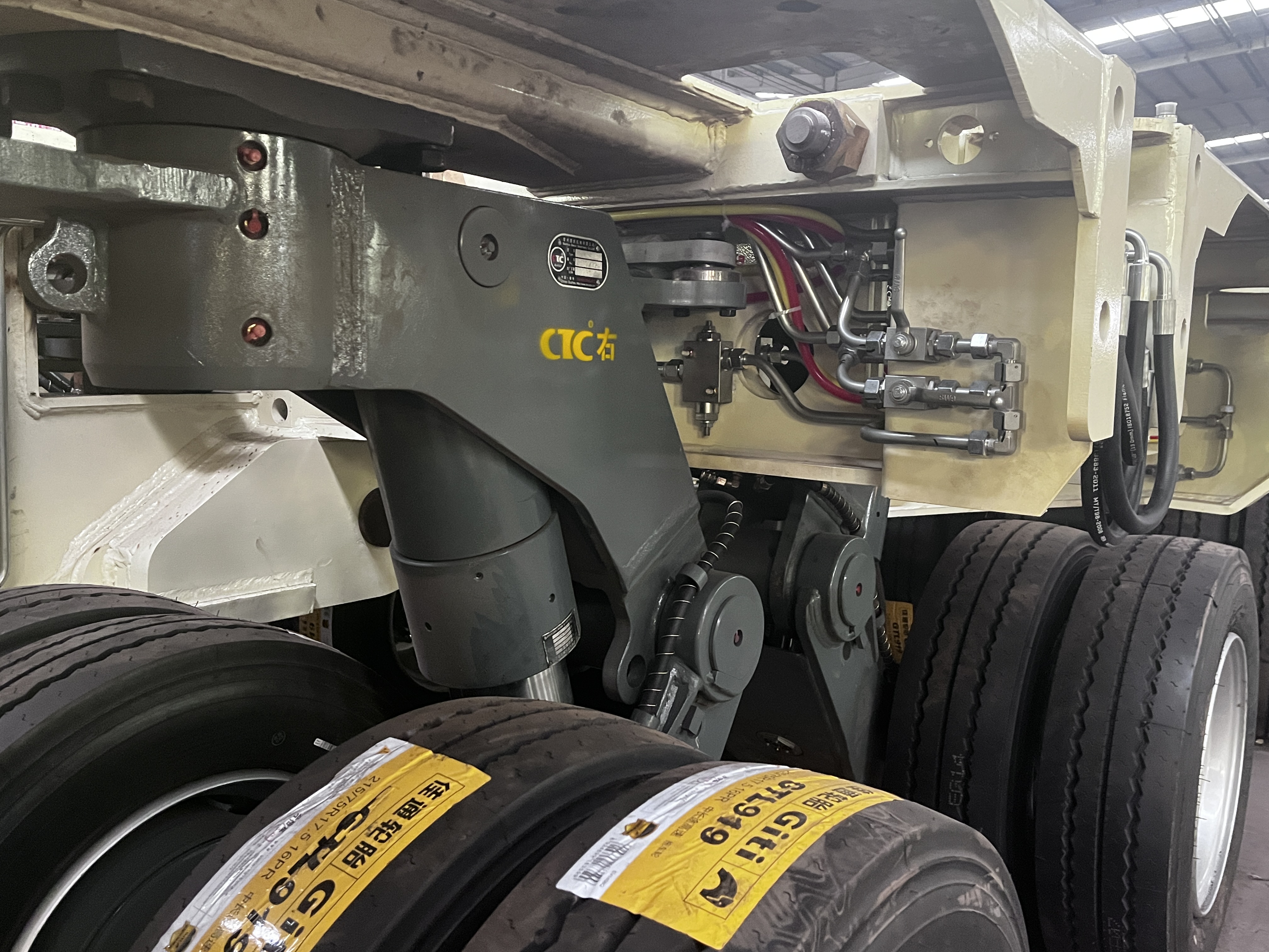 Close-up view of the robust CTC pendular axle and hydraulic suspension cylinder on the modular trailer, highlighting the complex steering and leveling hydraulic lines