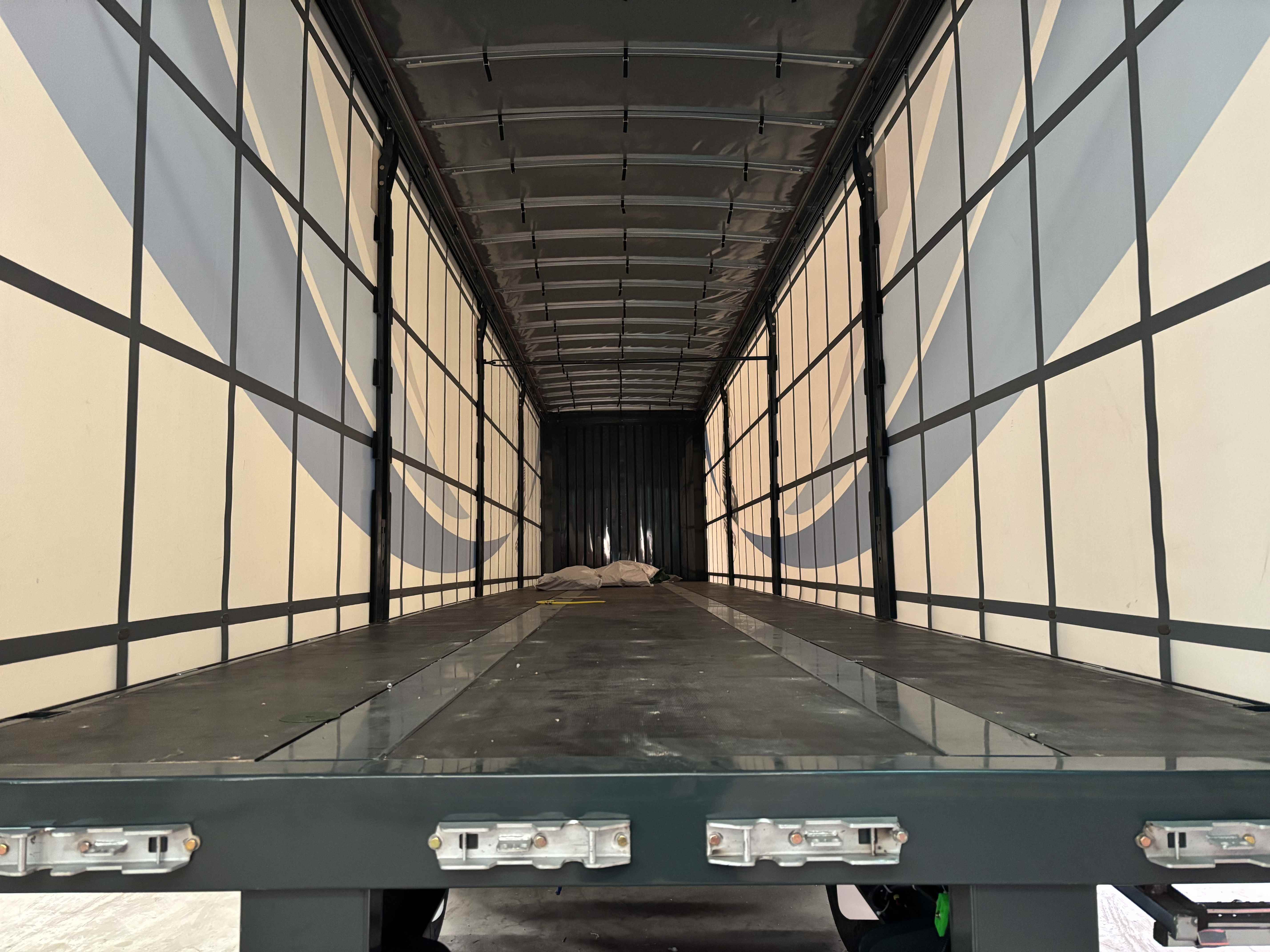 Interior view of the custom tri-axle curtain side trailer, highlighting the clean, anti-slip flooring and durable internal framework