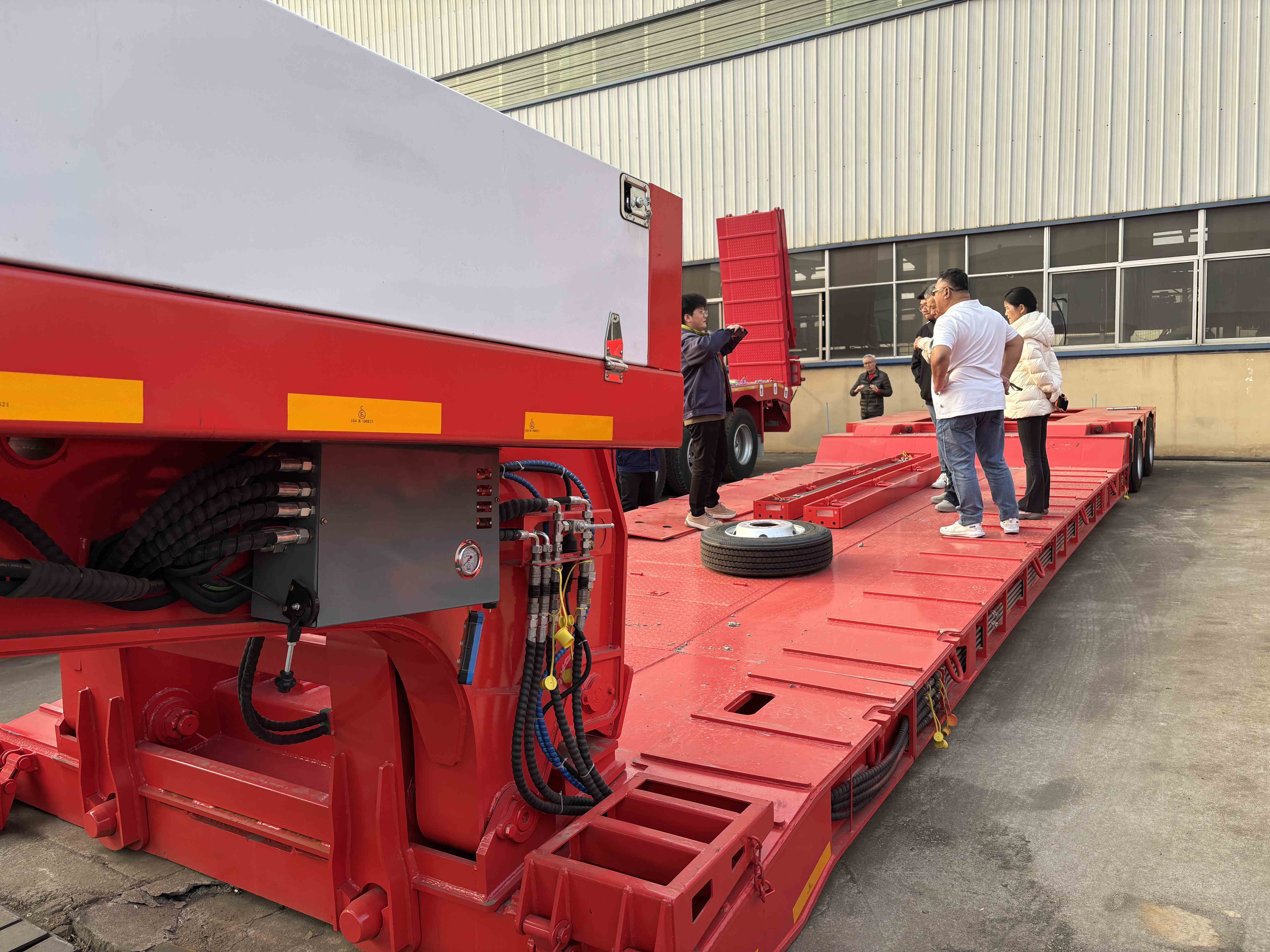 Malaysian clients inspecting the hydraulic controls and flat deck of the 2 axle RGN lowboy trailer at the manufacturing facility