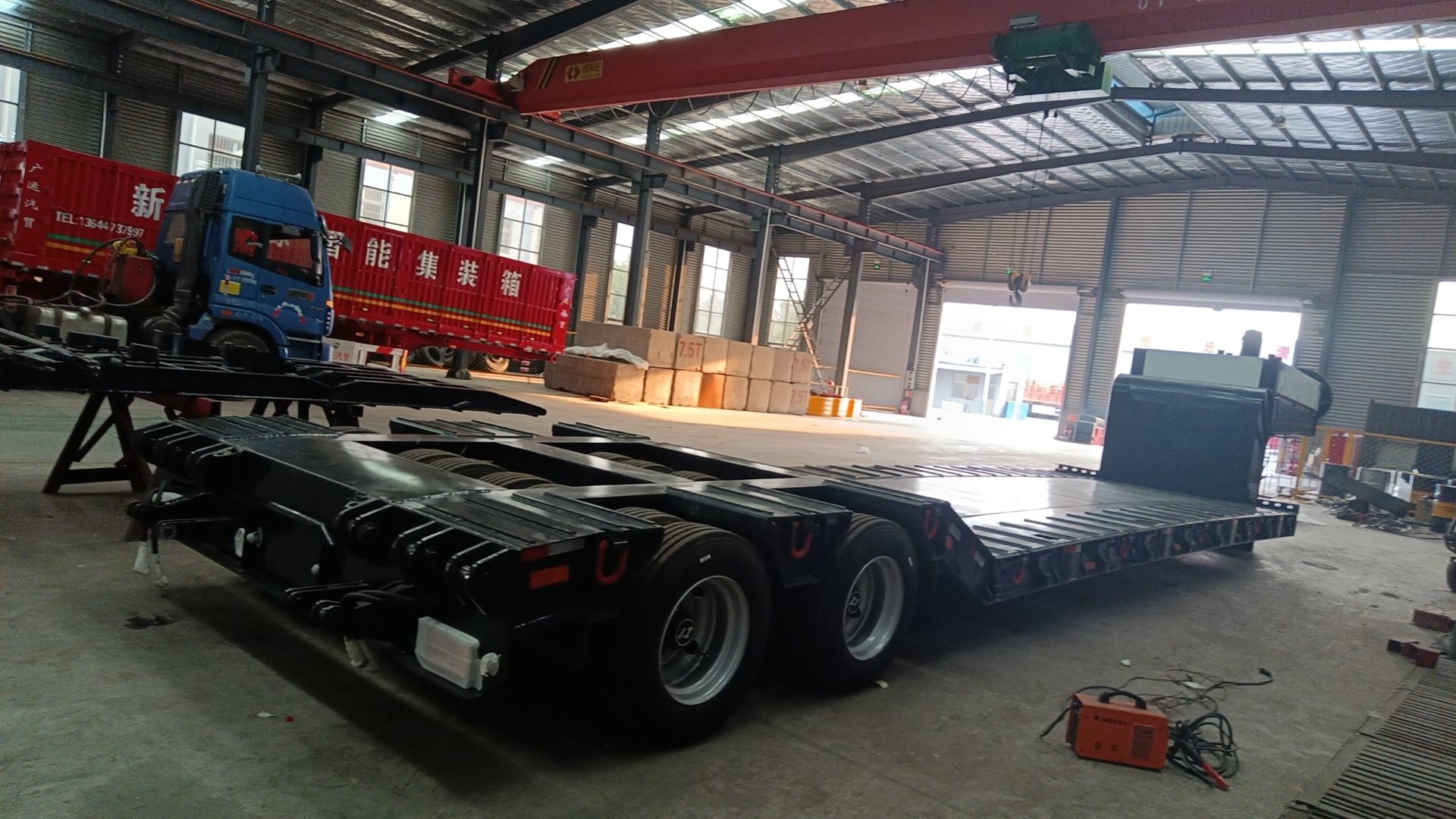 Rear-side technical shot of the empty white specialized lowbed trailer, focusing on the specialized line-axle configuration and robust tire setup for stable heavy cargo transport