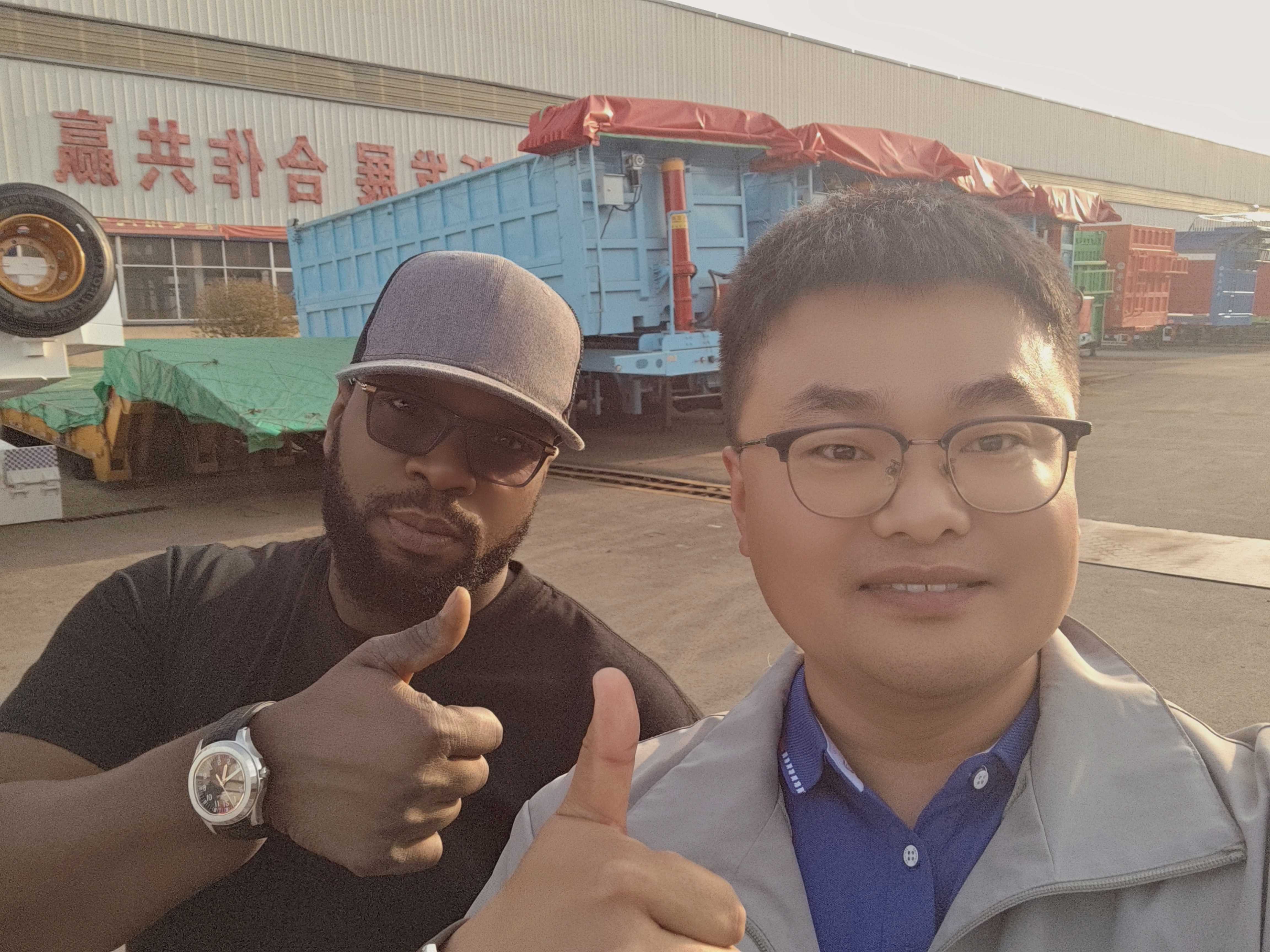 A group of representatives from a Congo logistics company visiting the HUAYUE manufacturing facility to inspect a specialized 3-axle removable gooseneck (RGN) lowboy trailer
