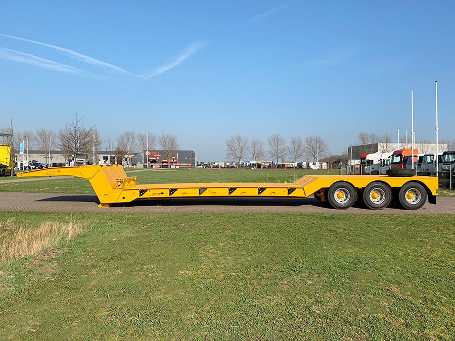 Full side view of a yellow HUAYUE 3-axle folding gooseneck trailer, showcasing its long flat deck and heavy-duty chassis designed for the Pakistan market