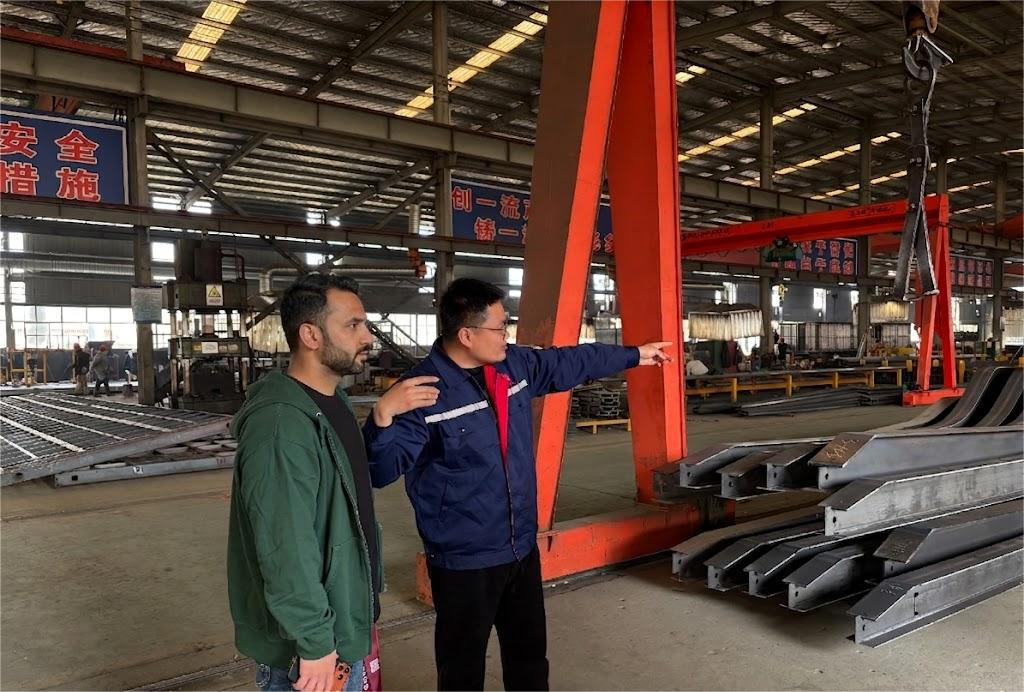 A Pakistani client inspecting heavy-duty steel chassis components with a HUAYUE engineer during a factory visit for a folding gooseneck trailer