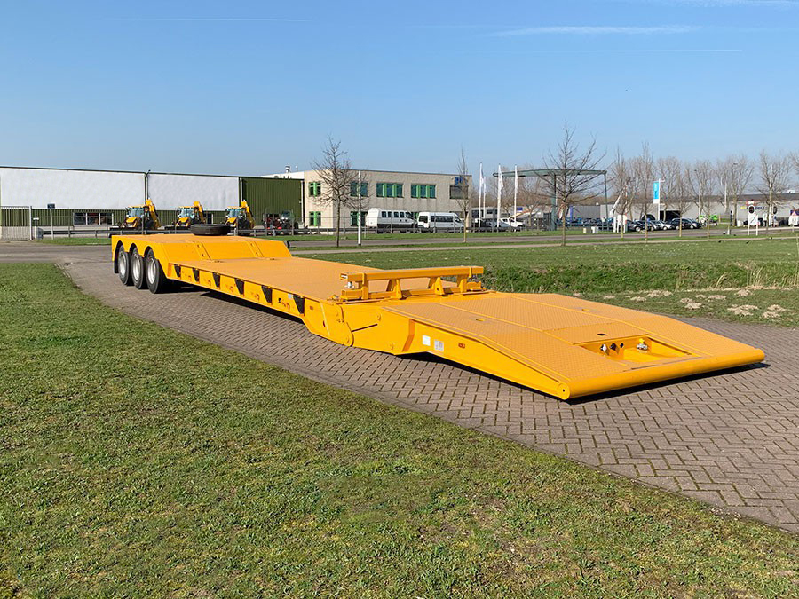 Front-loading view of the yellow folding gooseneck trailer with the neck fully lowered to the ground, creating a low-angle ramp for safe machinery loading