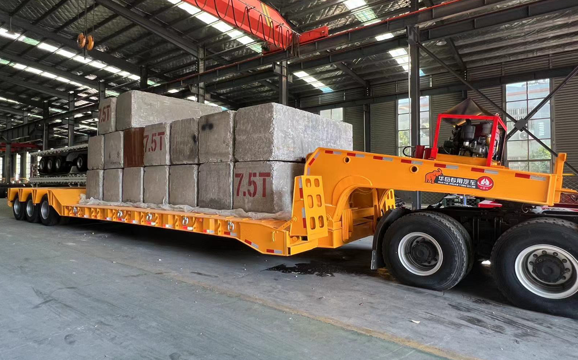 HUAYUE 3-axle RGN lowboy trailer undergoing extreme dynamic load testing with multiple 7.5-ton concrete blocks to verify the yield strength limit of the main beam.
