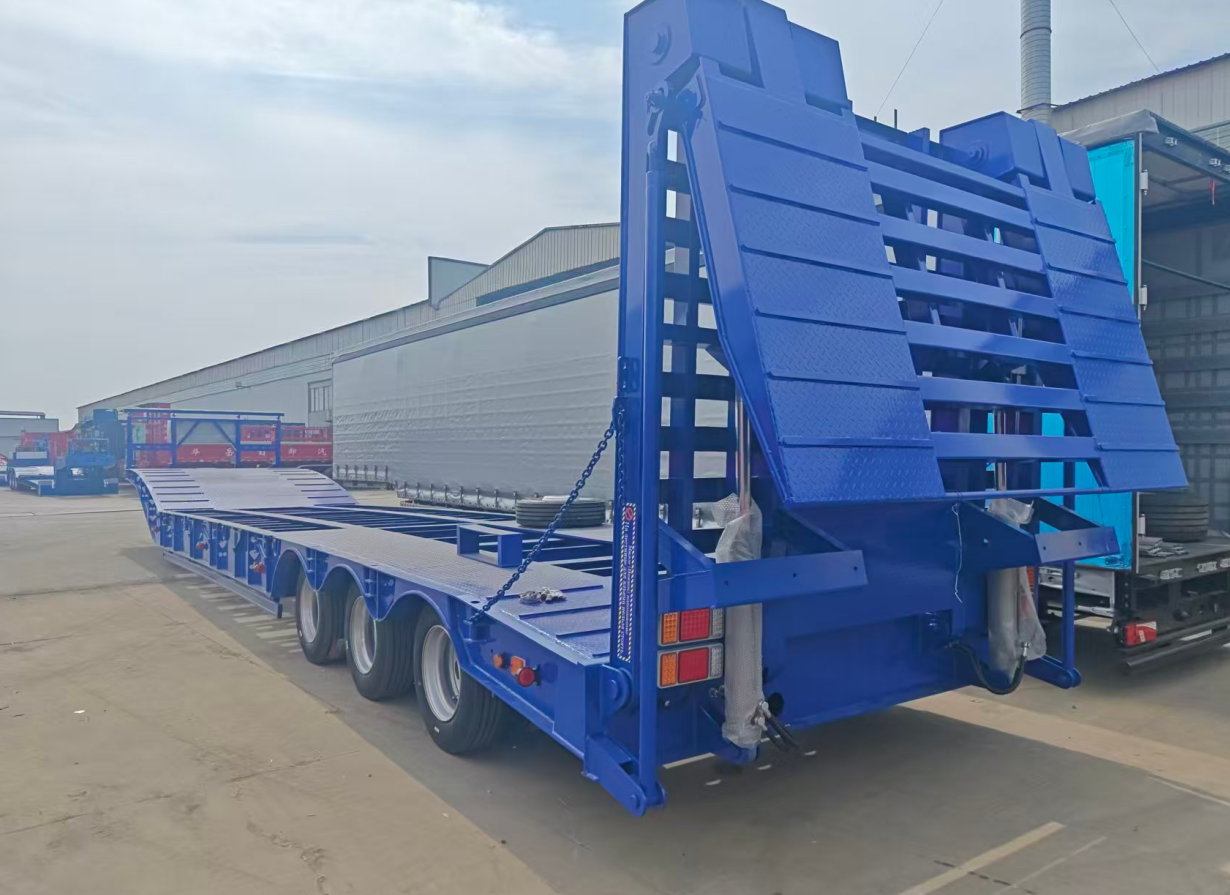 Rear perspective of the HUAYUE 3-axle lowbed trailer, showcasing the powerful cylinder-driven heavy-duty double-folding hydraulic ramps and high-traction checkered steel plates.