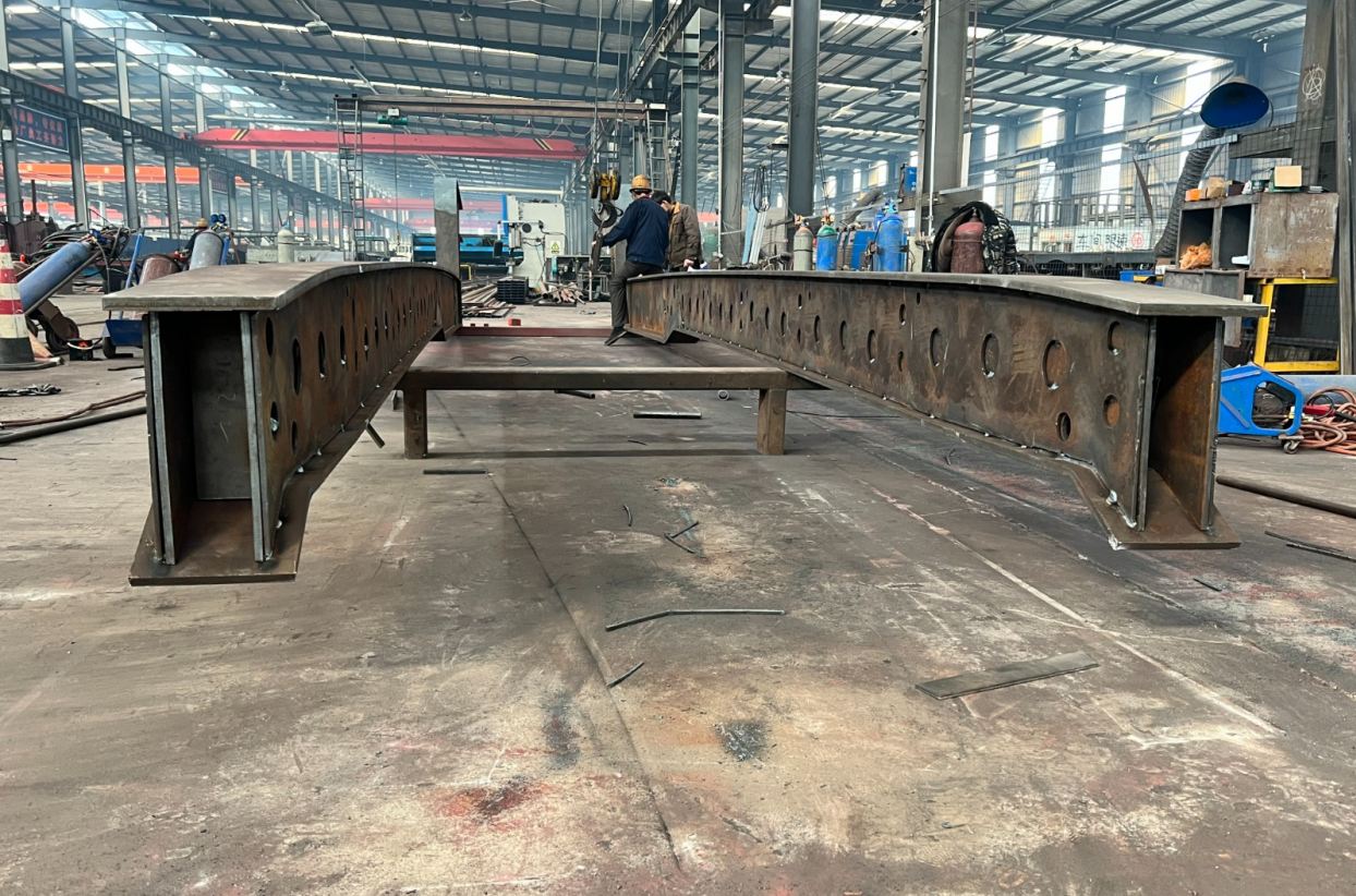 Two heavy-duty lowbed main beams being assembled in the HUAYUE workshop. The image clearly demonstrates a deliberate upward curve from the ends to the center while unladen—the core essence of Pre-Camber engineering.