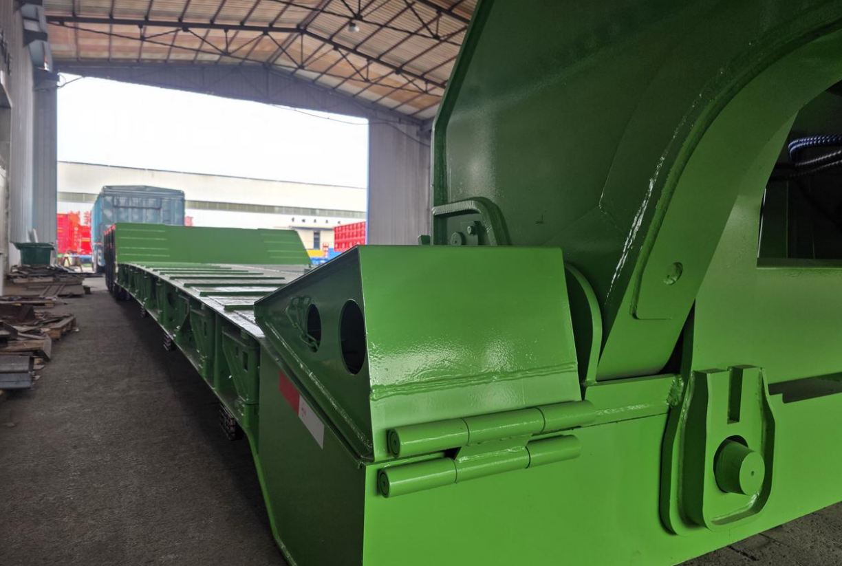 Side close-up of the HUAYUE heavy-duty lowbed trailer gooseneck transition zone, clearly showing the thick double-layered high-tensile steel web plates and heavy-duty mechanical pins designed to combat extreme braking inertia.