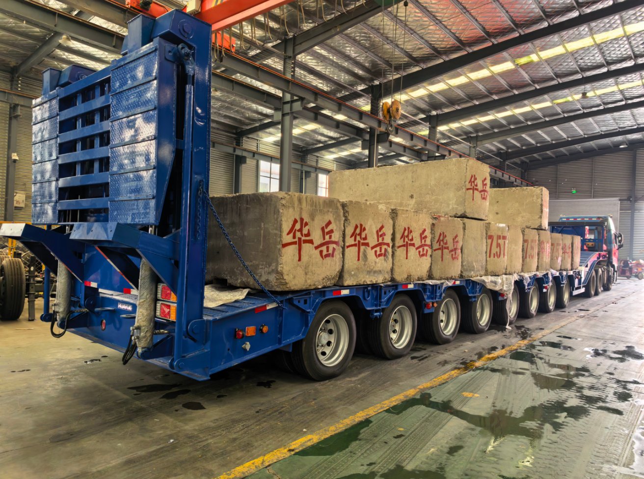 HUAYUE 8-axle heavy-duty lowbed trailer undergoing an extreme full-load test with concrete weights, featuring heavy-duty folding hydraulic ramps and a robust support system at the rear.