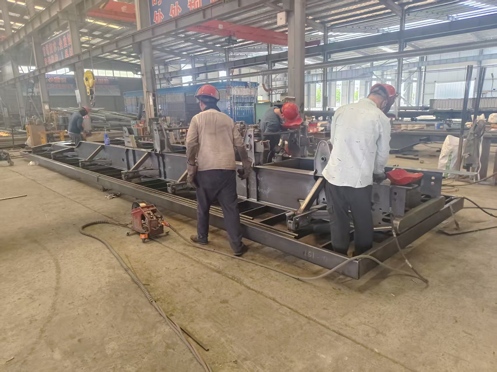 Engineers performing full-penetration welding on a heavy-duty trailer main beam engineered with precise pre-camber to completely eliminate sagging risks under heavy loads.