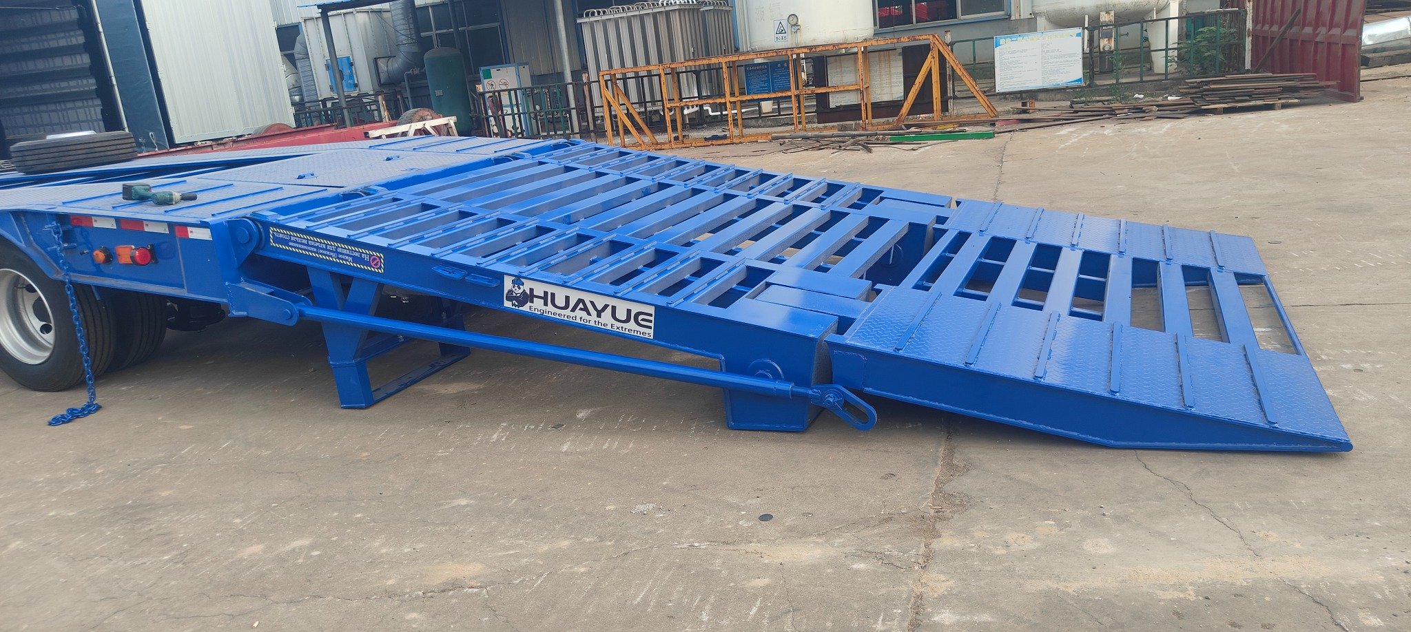 Rear view of a HUAYUE heavy-duty lowbed trailer showcasing folded high-strength double-folding hydraulic ramps and heavy-duty rear support legs, reducing wind resistance and providing extreme loading rigidity.