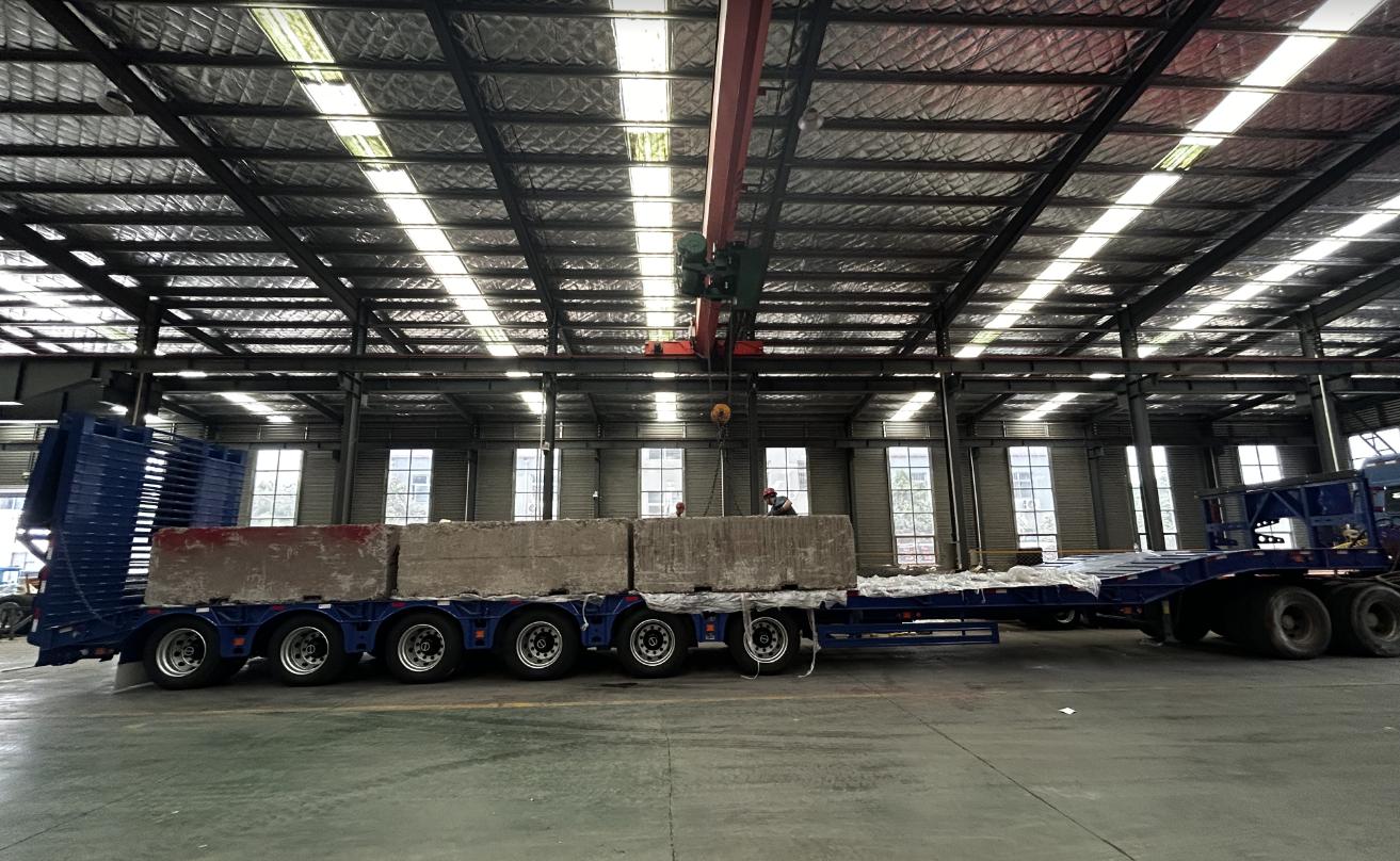 HUAYUE multi-axle heavy-duty trailer undergoing extreme load testing in the workshop with massive concrete blocks, demonstrating the deck and chassis's superior compressive strength and weight distribution.