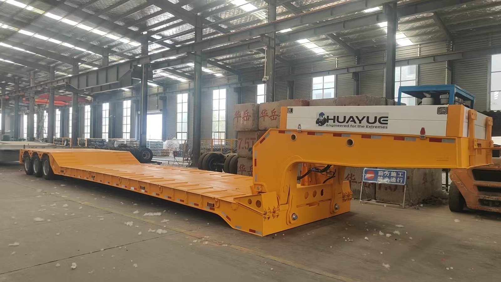 HUAYUE yellow Hydraulic Removable Gooseneck (RGN) trailer showing the gooseneck completely detached and the deck front resting flat on the ground, providing a 0° angle front-loading ramp.