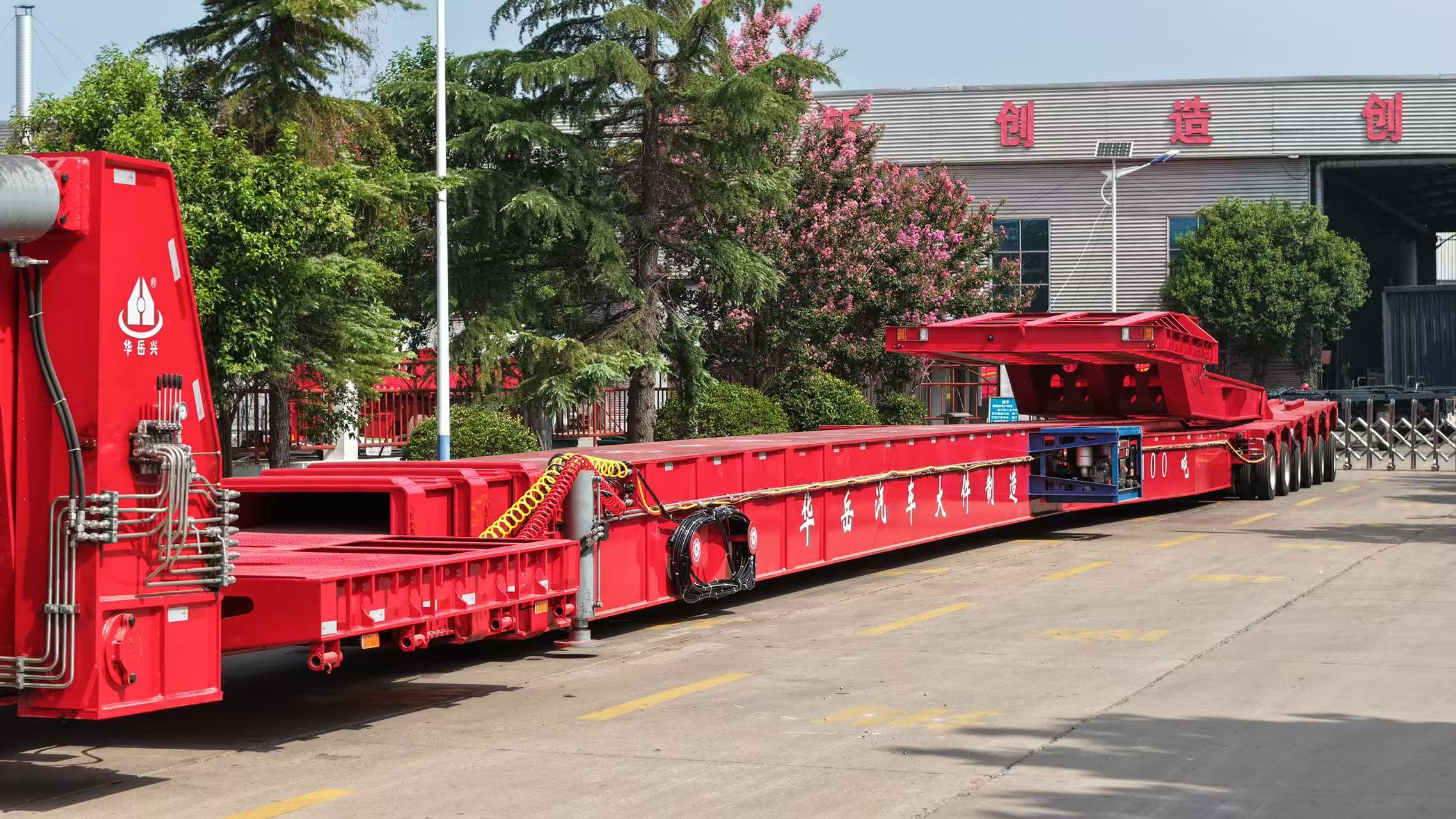 HUAYUE special red extendable lowboy trailer showing its high-strength box-type telescoping structure and highly flexible energy chain for line protection.