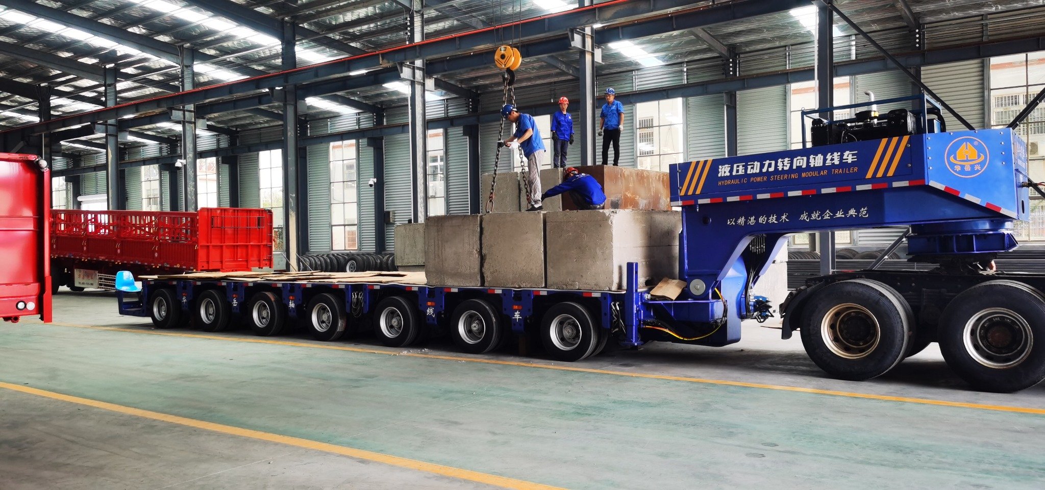 HUAYUE blue hydraulic power steering modular trailer undergoing extreme static load testing with heavy concrete ballast inside the fabrication plant.