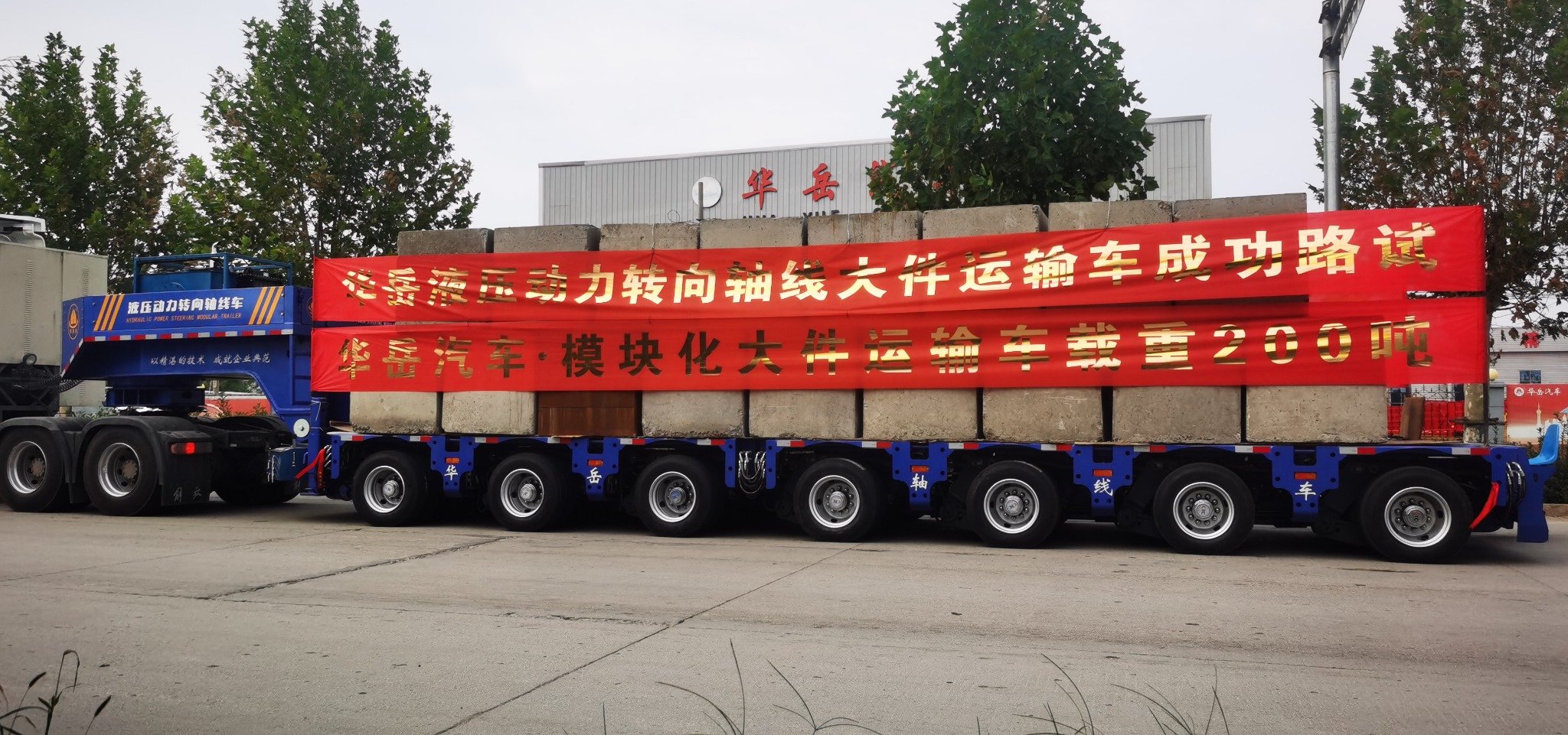 HUAYUE hydraulic power steering modular trailer carrying a massive 200-ton concrete test load, successfully passing its open highway road tests.
