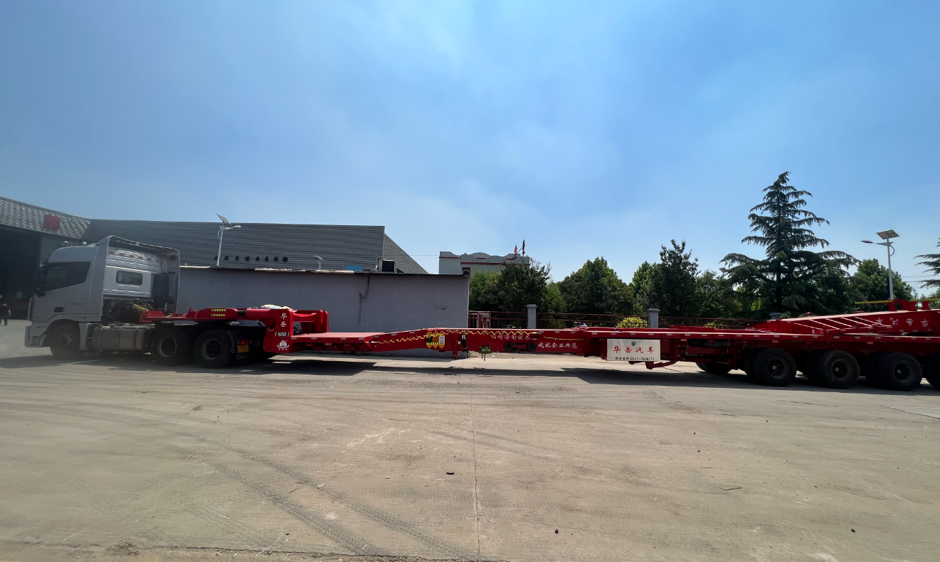 Close-up of the multi-stage box beam telescopic structure and rear hydraulic steering axles of a wind blade extendable trailer, showcasing its core deformation and steering technology.