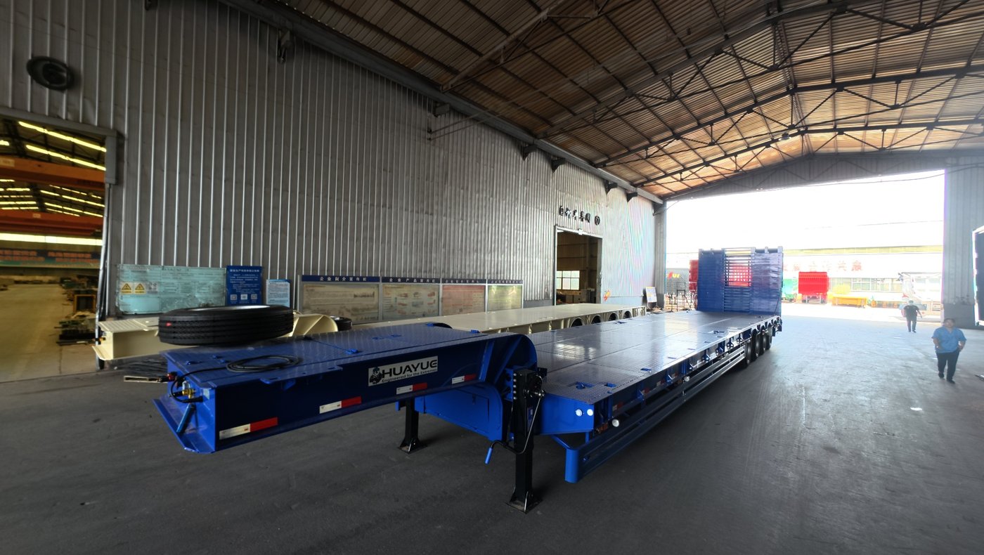 A HUAYUE heavy-duty lowbed semi-trailer smoothly transporting a massive crawler excavator on the highway, demonstrating the significant advantages of its ultra-low deck in handling bridge height restrictions.