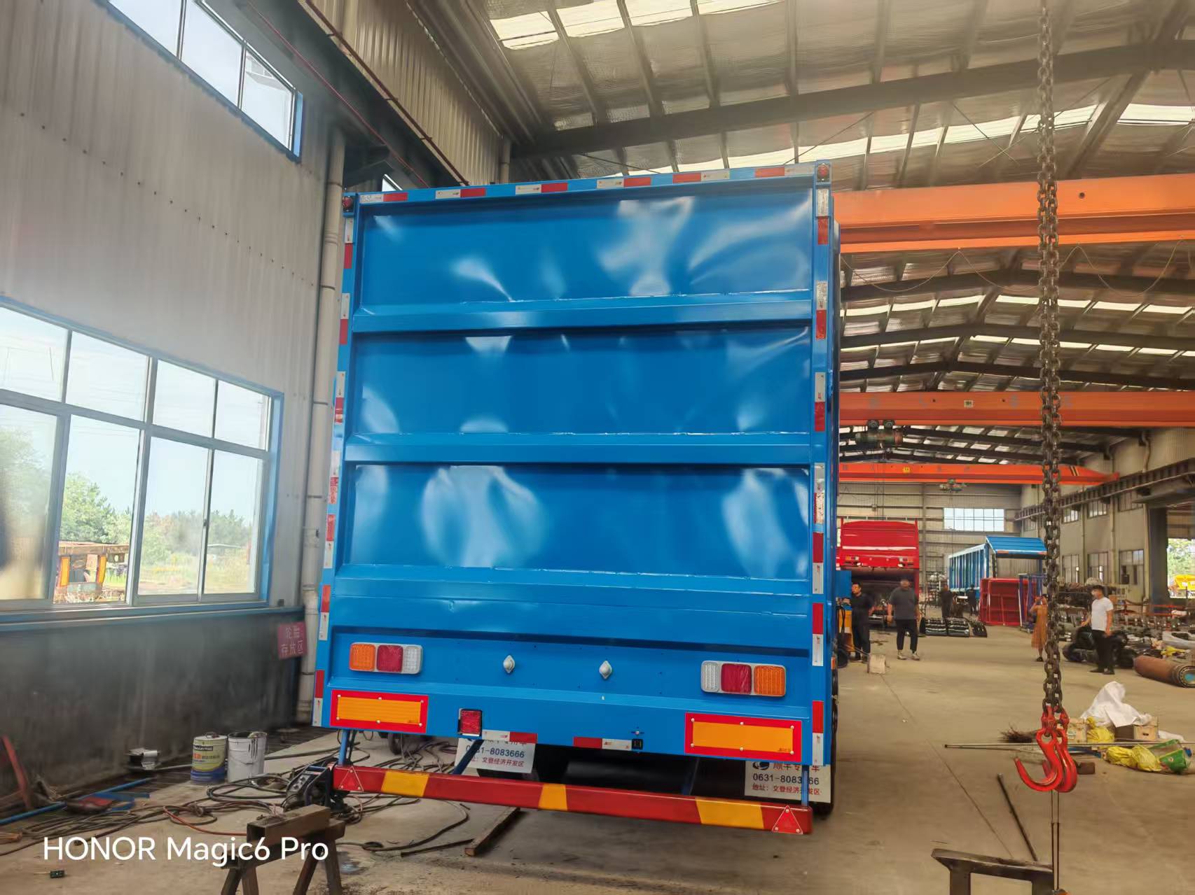 Rear view of a blue bulk-material semi-trailer in a workshop