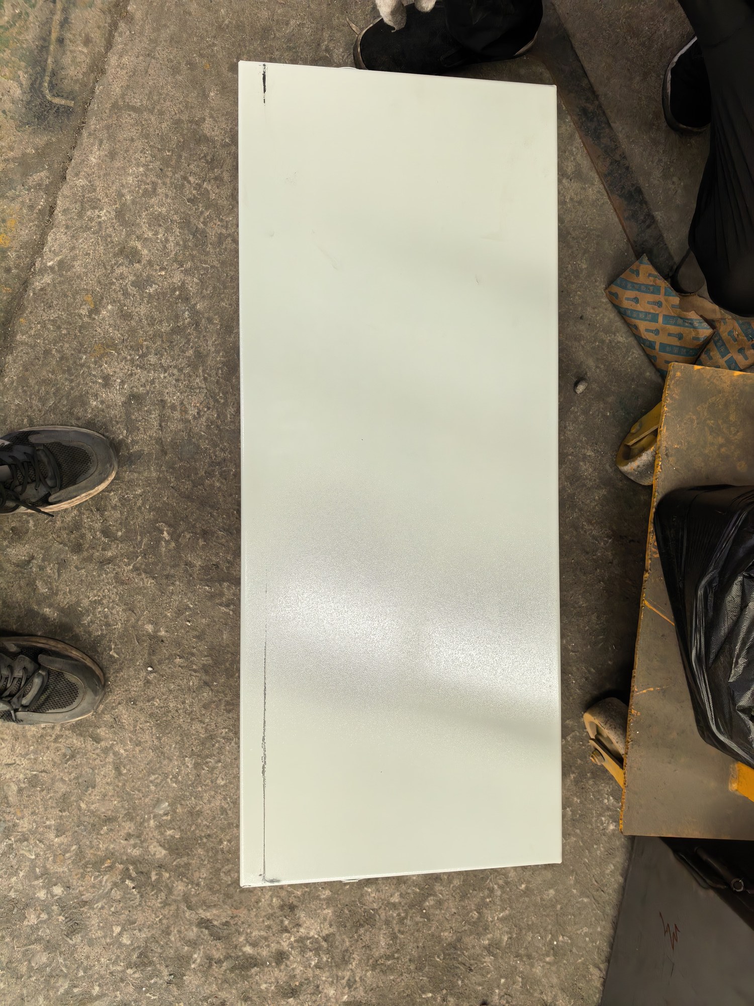 Light-coloured rectangular enclosure cover photographed during after-sales service preparation